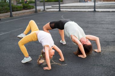 Küçük bir kız ve annesi açık hava spor sahasında briç oynuyorlar.