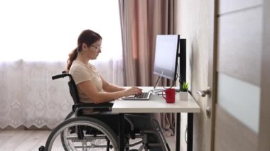 Caucasian woman with disabilities working at the computer while sitting in a wheelchair