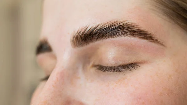 Close-up portrait of a woman after the procedure of correction and lamination of eyebrows