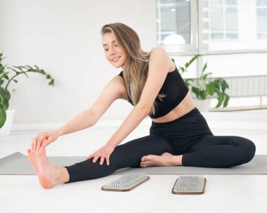 Beyaz kadın sadhu çivileri üzerinde durduktan sonra yoga minderine oturur.