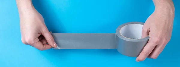 Woman holding silver scotch tape on blue background