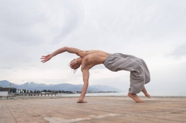 Çakıl taşlı plajda ters takla atan beyaz bir adam.