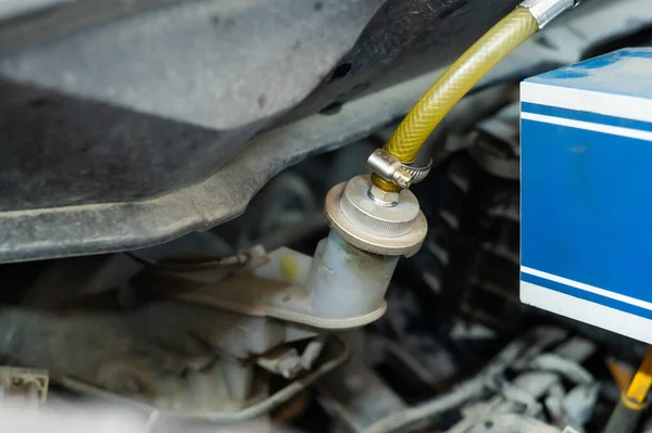 Automated change of brake fluid in a car service. Car bonnet