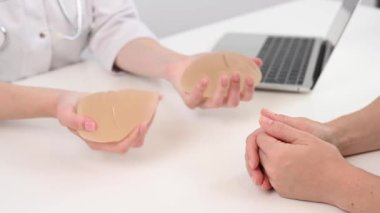 Caucasian woman and plastic surgeon touching and choosing breast implants