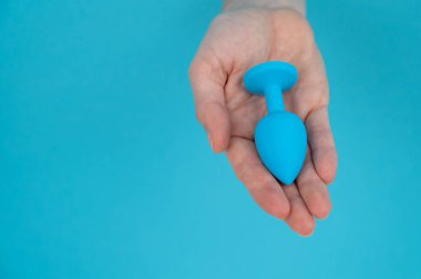 Mavi arka planda mavi anal tıpa tutan bir kadın.