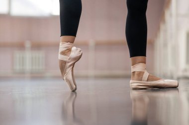 Close-up but ballerinas in pointe shoes in a dance class. The woman stands on one toe
