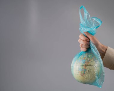 Beyaz arka planda plastik bir torba içinde bir kadın elinde bir küre tutuyor.