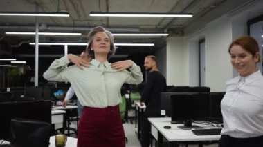 Four office workers warm up during a break. Employees do fitness exercises at the workplace. Slow motion