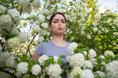 Mutsuz bir kadın, burnunda mandalla lanet bir parkta yürüyor.