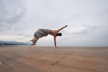 Çakıl taşlı plajda ters takla atan beyaz bir adam.
