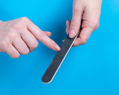 Woman filing her nails on a blue background