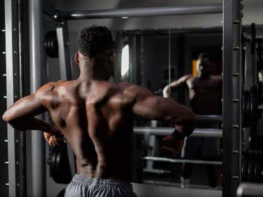 Yakışıklı afro-amerikalı adam spor salonunda sırt kaslarını gösteriyor.