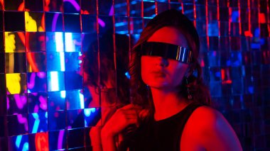 Close-up portrait of a caucasian woman in sunglasses in neon light against a mirror wall