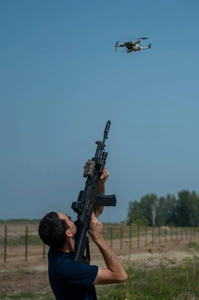 Man aiming to shoot a rifle at a flying drone outdoors