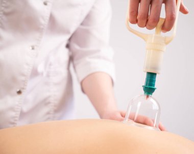 Kadın masaj terapisti hastaların sırtında süpürge kullanıyor.