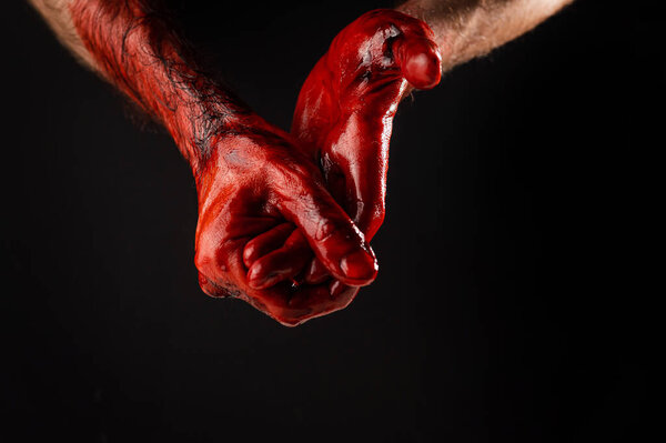 Mens palms are stained with blood on a black background