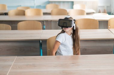 Sınıfta sanal gerçeklik gözlüğü takan beyaz bir kız öğrenci.