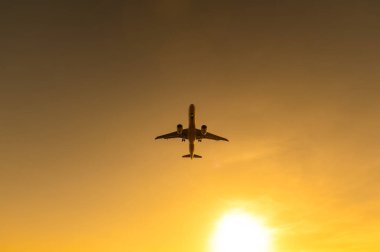 Gün batımında uçan bir uçağın alt görüntüsü.