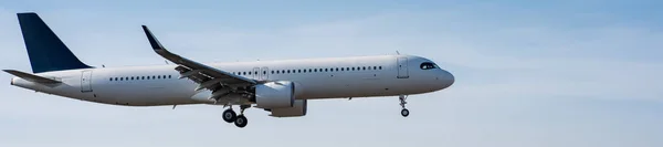 Side view of an airplane landing against a blue sky. Widescreen