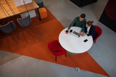 Yuvarlak masada dizüstü bilgisayarla çalışan kadın ve erkeğin üst görüntüsü