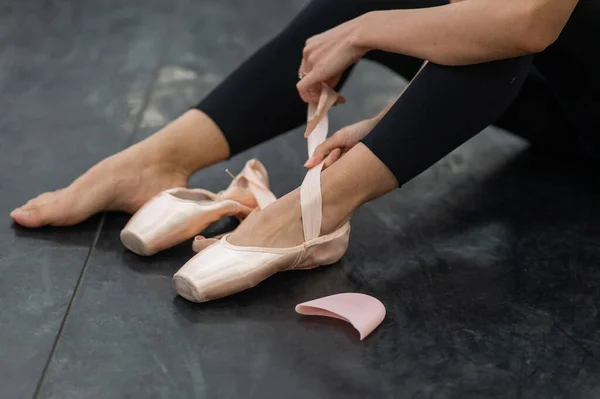 stock image A faceless woman puts on pointe shoes. Close-up of ballerinas legs