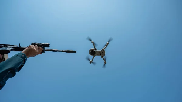 Człowiek Celuje Karabinu Latającego Drona Przeciwko Błękitnemu Niebu — Zdjęcie stockowe