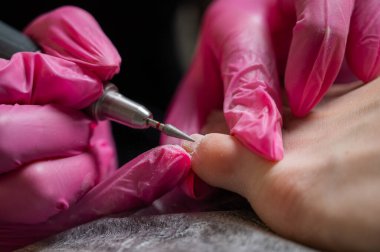 Usta müşteriye donanım pedikürü yapıyor. Kütikül tedavisi