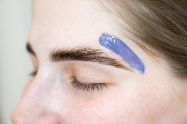 Kaş düzeltmesi. Usta, ahşap bir spatulayla balmumu sürüyor.