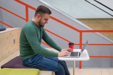 Ortak çalışma alanında dizüstü bilgisayarda çalışan beyaz bir adam. Boşluk aç