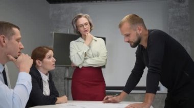The female boss evaluates the work of subordinates. Designers engineers at a meeting