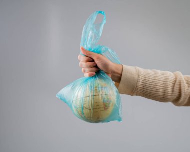 Beyaz arka planda plastik bir torba içinde bir kadın elinde bir küre tutuyor.