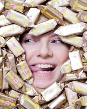 The face of a Caucasian woman surrounded by Rakhat chocolates. The girl shows her tongue.