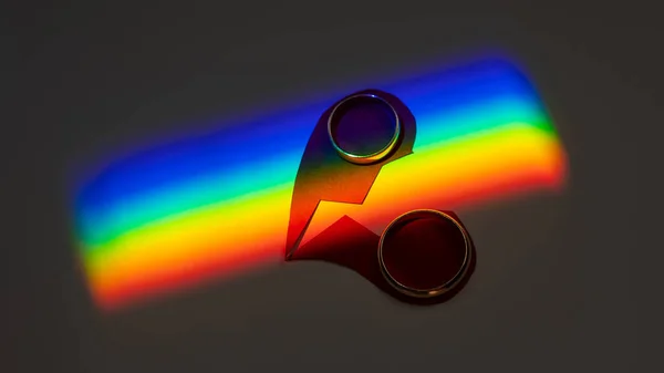 Rainbow beam on wedding rings with a broken heart. lgbt flag
