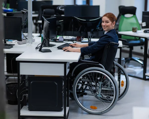 Stock image Caucasian smiling woman in wheelchair at work desk