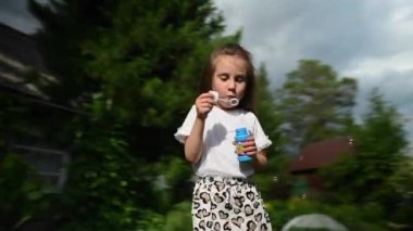 Küçük kız dışarıda sabun köpüğüyle oynuyor. Video 360 derece