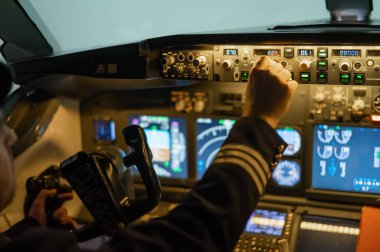 Bir adam uçuş simülatöründe pilot olmak için çalışıyor. Erkek eli, bir uçağın kontrol panelinin üzerinde.