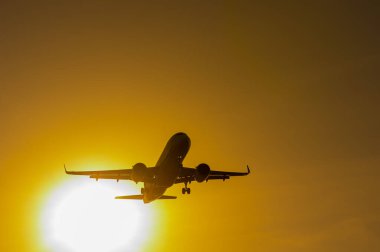 Gün batımında uçan bir uçağın alt görüntüsü.