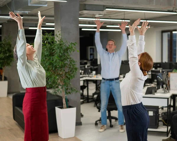 四个办公室职员在休息时热身 雇员在工作场所做健身锻炼 — 图库照片