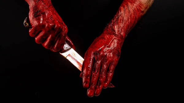 黒い背景に血のナイフを手で拭く男 — ストック写真