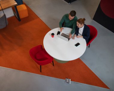 Yuvarlak masada dizüstü bilgisayarla çalışan kadın ve erkeğin üst görüntüsü