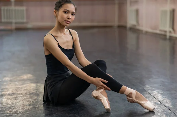 Asian Woman Dressed Black Bodysuit Leggings Pointe Shoes Sits Floor — 스톡 사진
