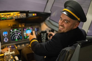 Uçuş simülatöründe otururken gülümseyen beyaz sakallı adam. Pilot kokpitte.