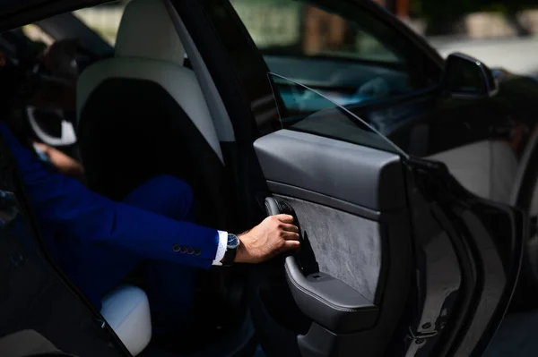 stock image A man in a blue suit opens the car door. Close-up of a mans hand with an expensive watch