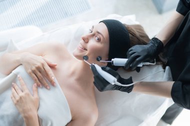 Genç beyaz kadın mikro akım terapi prosedürü uyguluyor. Güzellik bürosu