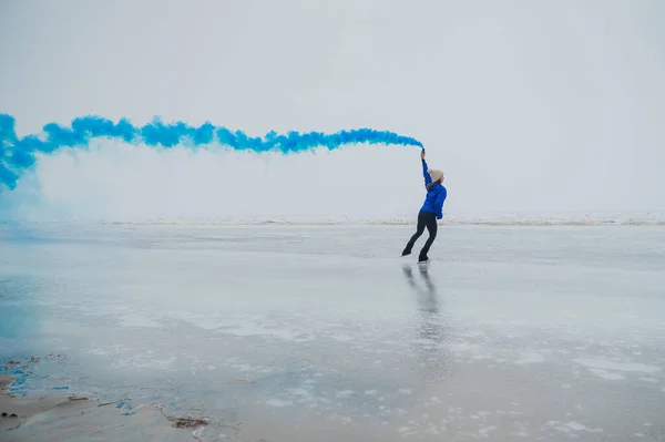 白人女性は凍った湖でスケートをしている彼女の手に青い煙を持っている — ストック写真