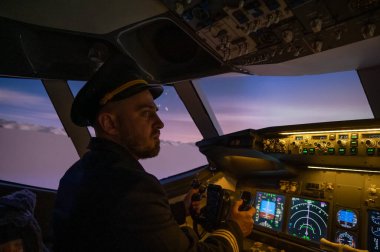Bir adam uçak simülatöründe pilot olmak için okuyor.