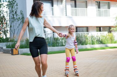 Anne kızının paten kaymasını öğrenmesine yardım ediyor.