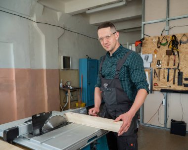 Marangoz dairesel bir makinede ahşap bir tahta keser.