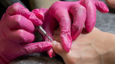 Usta müşteriye donanım pedikürü yapıyor. Kütikül tedavisi