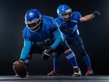 Two American football players are ready to start the game on a black background